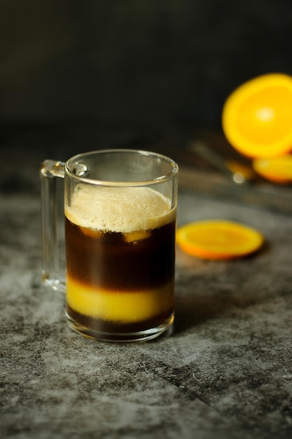 La mano di un uomo spreme il succo di un'arancia fresca in un bicchiere di caffè ghiacciato