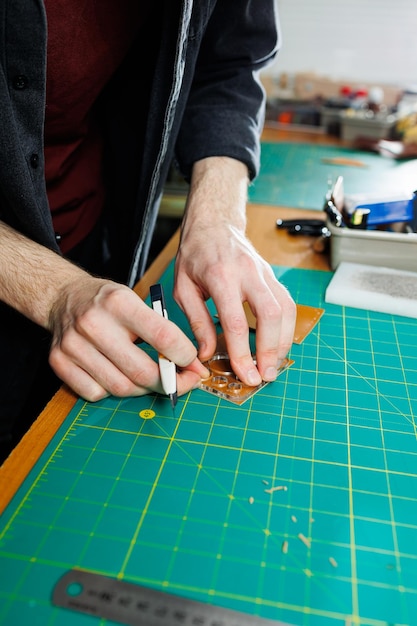 La mano di un uomo tiene pezzi di pelle per un portafoglio in pelle nel suo laboratorio Il processo di lavorazione della pelle marrone naturale L'artigiano tiene il mestiere