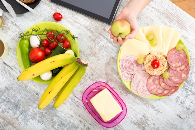 La mano di una donna con cibo e tablet