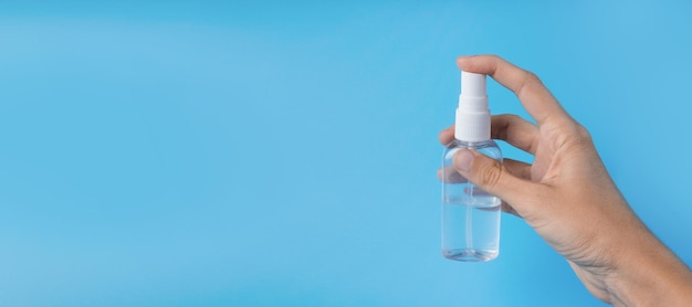 La mano di una donna con un antisettico su un primo piano sfondo blu. Il concetto di igiene e pulizia. Disinfettante. bandiera. Copia spazio