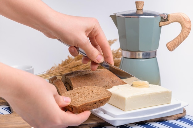 La mano di una donna fa un panino con il primo piano del pane di segale e del burro