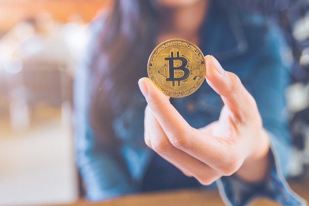 La mano di una donna in possesso di una valuta, bitcoin.