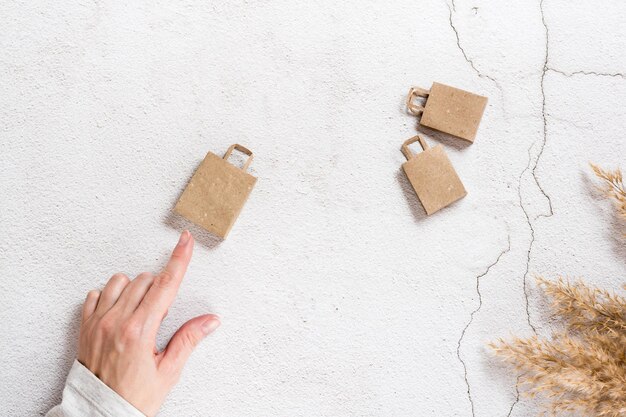 La mano di una donna indica borse della spesa artigianali di carta su uno sfondo di cemento Vista dall'alto