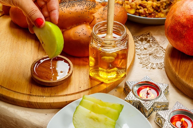 La mano di una donna intinge una mela nel miele durante un pasto di Rosh Hashanah