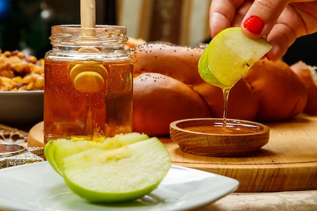 La mano di una donna intinge una mela nel miele durante un pasto di Rosh Hashanah