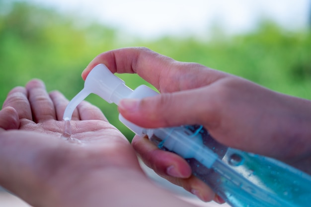 La mano di una donna preme un gel per lavarsi le mani e uccidere virus o batteri o germi. Prevenzione della diffusione del virus covid-19 mediante lavaggio a mano, sfregamento con gel alcolico al 75%