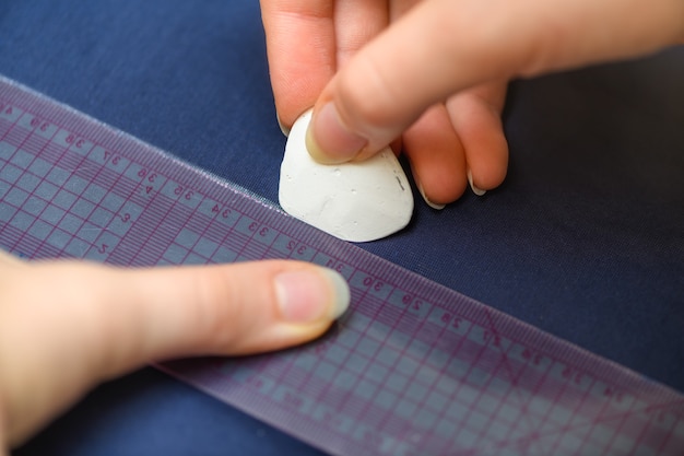 La mano di una donna segna la linea sul tessuto con il gesso per tagliare un indumento