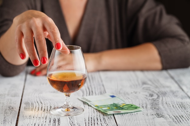 La mano di una donna tocca un bicchiere di cognac