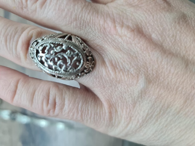 La mano di una persona con un grande anello d'argento con sopra una grossa pietra.