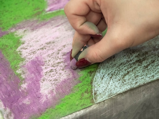 La mano è in movimento Disegno con primo piano di pastelli Donna che disegna bellissimi fiori di croco con pastelli morbidi a tavola Primo piano