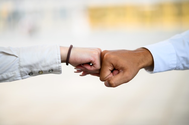 La mano è un pugno che tocca la parte anteriore dell'edificio alto. Forza di cooperazione e saluto covid