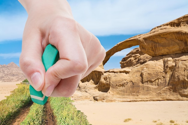 La mano elimina la sabbia nel deserto con la gomma