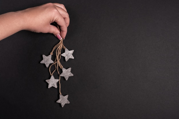 La mano femminile che tiene le stelle di legno con la corda, piano distende il nero