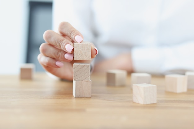 La mano femminile costruisce la torre dai cubi di legno