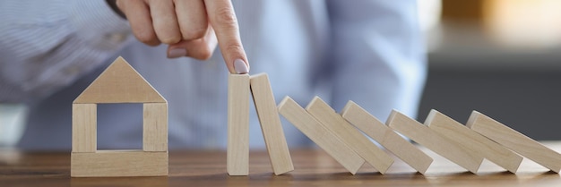 La mano femminile ha smesso di cadere blocchi di legno vicino alla miniatura di casa