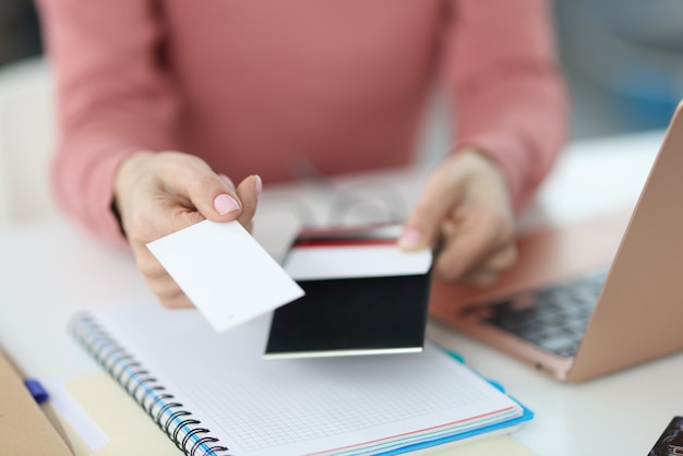 La mano femminile porge un biglietto da visita sul posto di lavoro. Stampa e realizzazione di biglietti da visita concetto