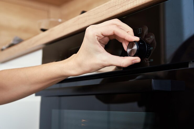 La mano femminile sceglie il programma di cottura sul pannello di controllo del forno elettrico donna che utilizza il forno elettrico moderno ho