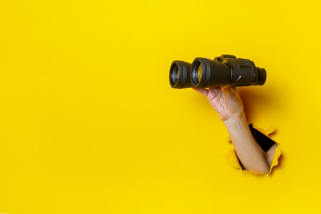 La mano femminile tiene il binocolo nero