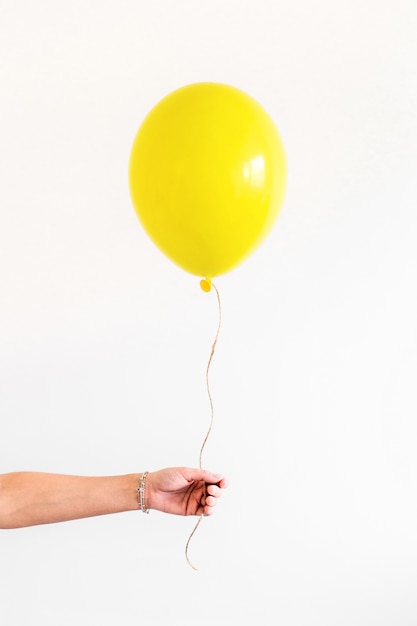 La mano femminile tiene il pallone giallo. Minimo concetto di festa