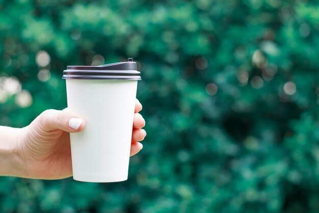 La mano femminile tiene la tazza di caffè di carta