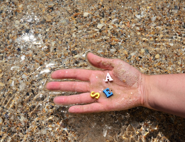 La mano femminile tiene le lettere multicolori di legno