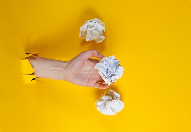 La mano femminile tiene le palle di carta sgualcite attraverso la carta gialla lacerata. Concetto di business idea minimalista