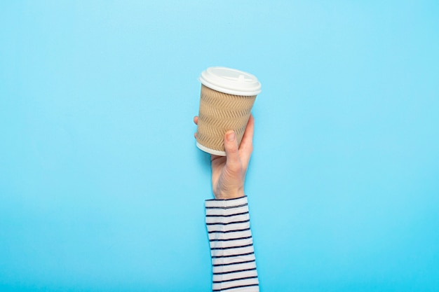 La mano femminile tiene un bicchiere di carta con caffè