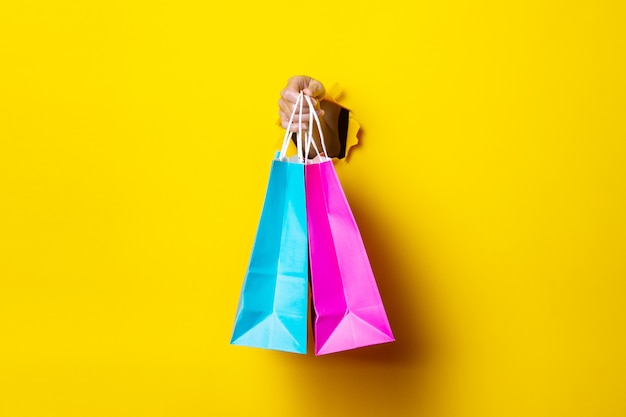 La mano femminile tiene una borsa della spesa rosa e blu