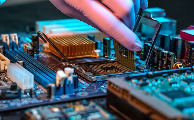 La mano guantata degli ingegneri tiene il chip della CPU sullo sfondo della scheda madre