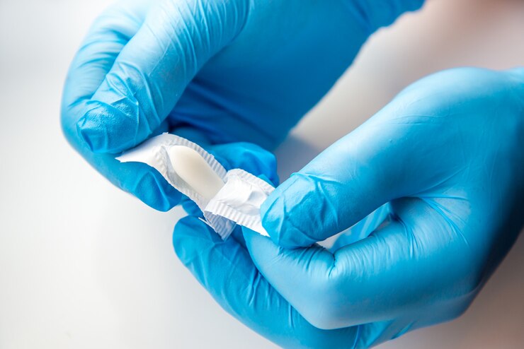 La mano guantata del dottore apre una supposta medica