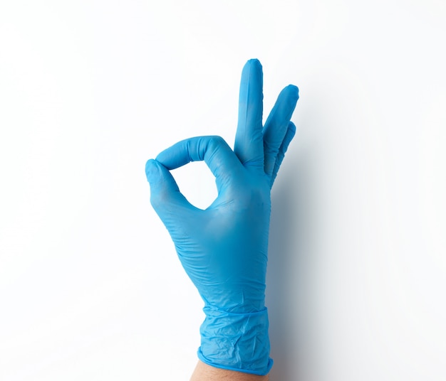 La mano in guanto medico blu mostra il gesto giusto, priorità bassa bianca