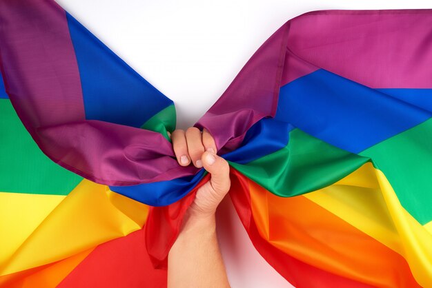 La mano maschile detiene una bandiera arcobaleno simbolo della comunità LGBT