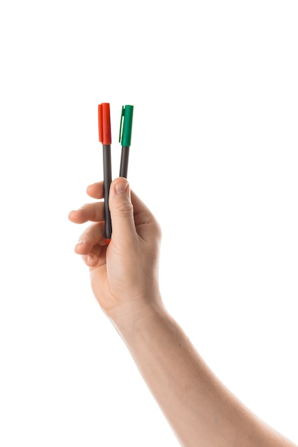 La mano maschile tiene due pennarelli rossi e verdi o un pennarello. Isolato su sfondo bianco.