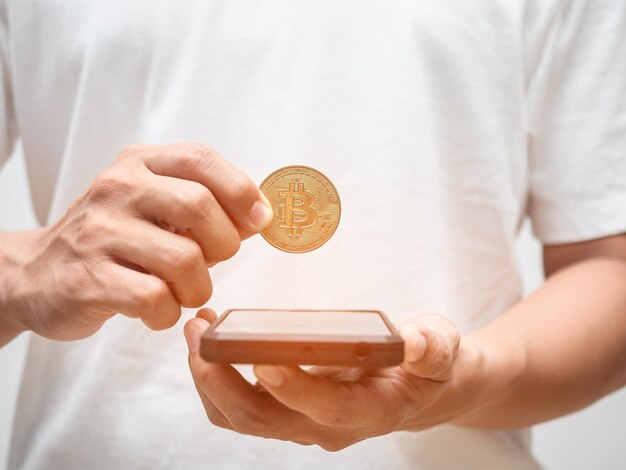 La mano maschio del primo piano raccoglie bitcoin dal concetto di denaro digitale dello schermo del telefono cellulare