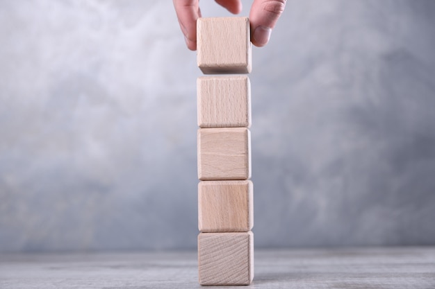 La mano mette cubo di legno bianco