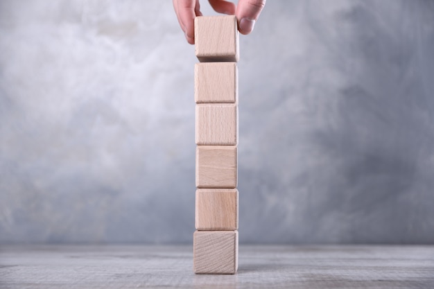 La mano mette cubo di legno bianco