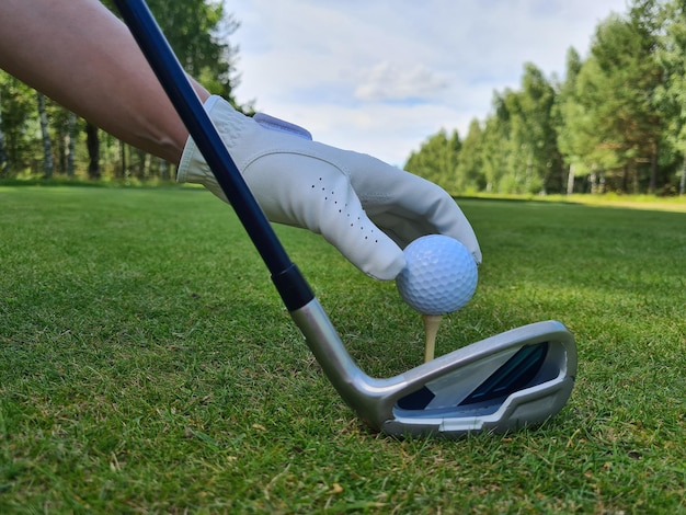 La mano mette la pallina da golf sul supporto con la mazza sul campo da golf