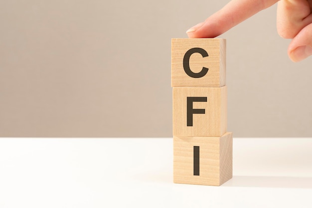 la mano mette un cubo di legno con la lettera CFI - abbreviazione di Custom Factory Integration. concetto di affari. spazio per il testo a sinistra. vista frontale