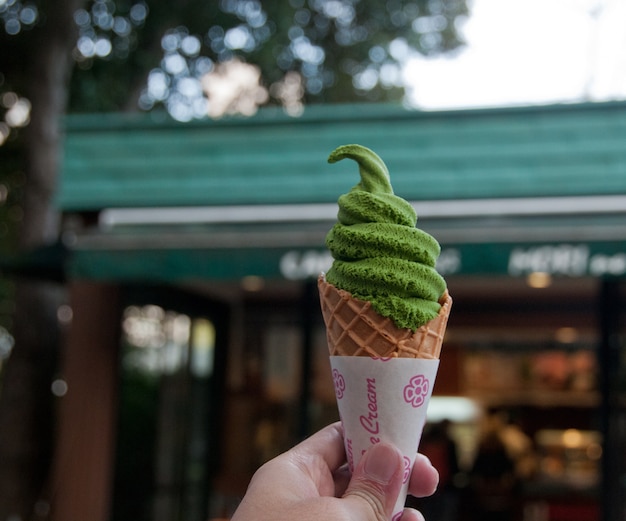 La mano sinistra tiene un gelato soft a base di tè verde matcha a Tokyo