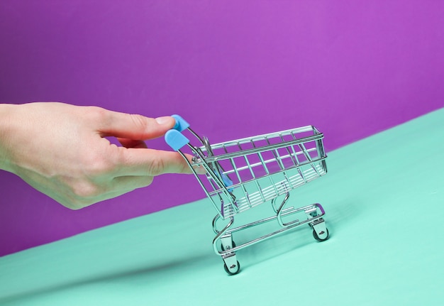 La mano spinge verso l'alto il mini carrello vuoto inclinato