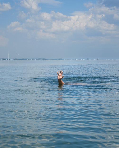 La mano sporge dall&#39;acqua nel mezzo dell&#39;oceano