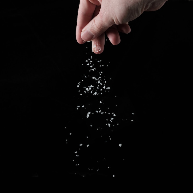 Foto la mano spruzza sale su sfondo nero