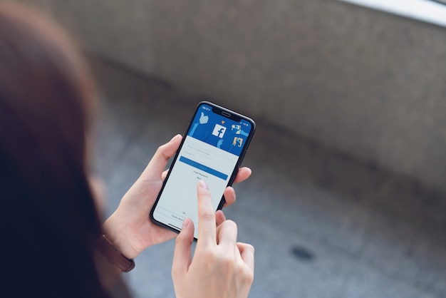 La mano sta premendo lo schermo di Facebook sullo smartphone