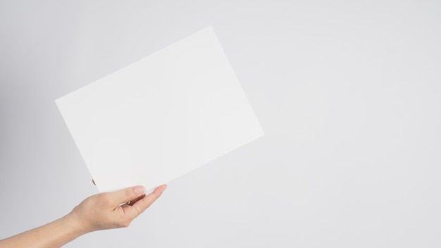 La mano sta tenendo la carta A4 vuota in bianco su fondo bianco.