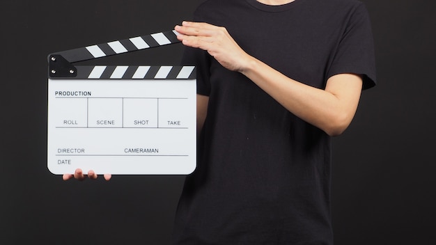 La mano tiene il bordo bianco o l'ardesia cinematografica utilizzata nella produzione di video e nell'industria cinematografica su sfondo nero.