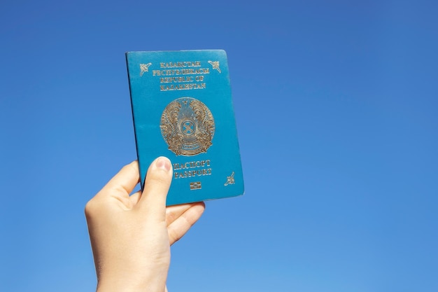 La mano tiene il passaporto nazionale della Repubblica del Kazakistan sullo sfondo del cielo blu