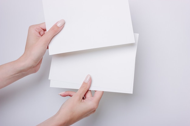 La mano tiene la carta A5 per la presentazione o l'inserto di design. Stile minimalista su uno sfondo grigio.