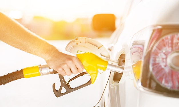 La mano tiene la stazione di servizio, la mano tiene una pompa del carburante per auto