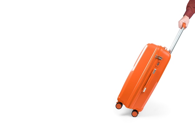 La mano tiene la valigia arancione su sfondo bianco Valigia da viaggio in plastica arancione con maniglia a cerniera e serratura vista laterale ravvicinata