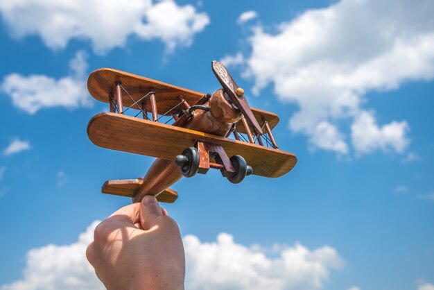 La mano tiene un aereo di legno sullo sfondo della nuvola